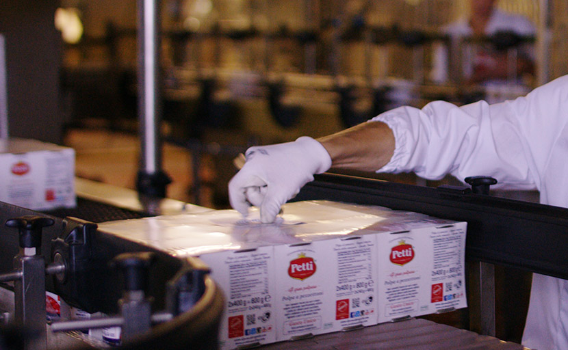 A worker manually attaches particular labels to products in the packaging phase of the cluster